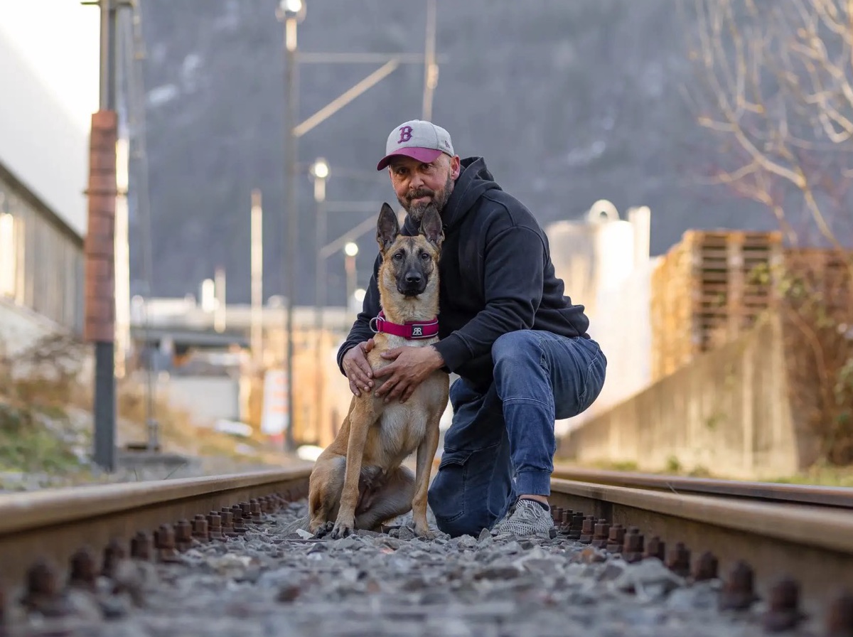 Marcel kniet mit seinem Malinois auf den Bahngleisen und liest ruhig dessen Körpersprache